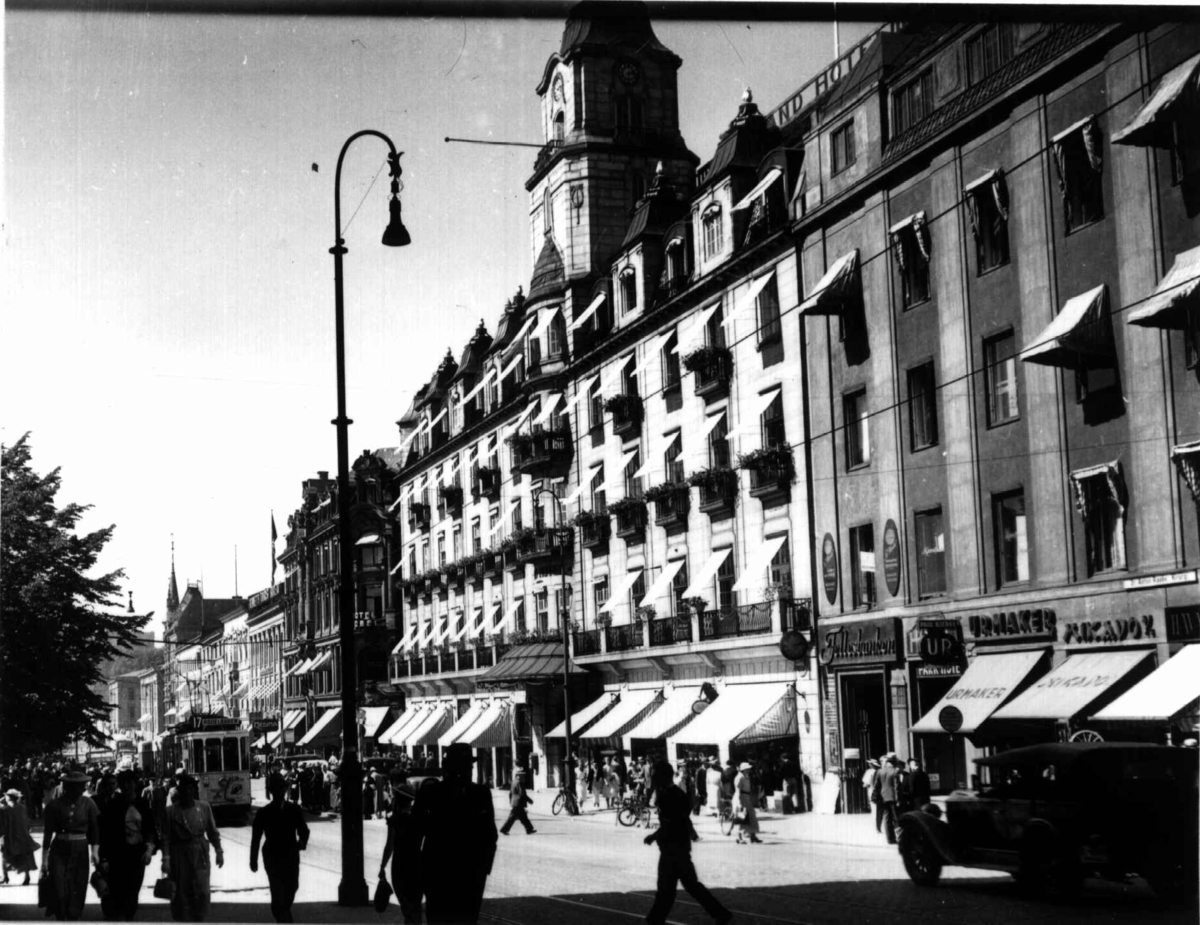 Hermann Christian Neupert, Karl Johans gate, Oslo 1936 sett fra Grand hotell opp mot Universitetet. Trafikk med fotgjengere, biler og trikk.