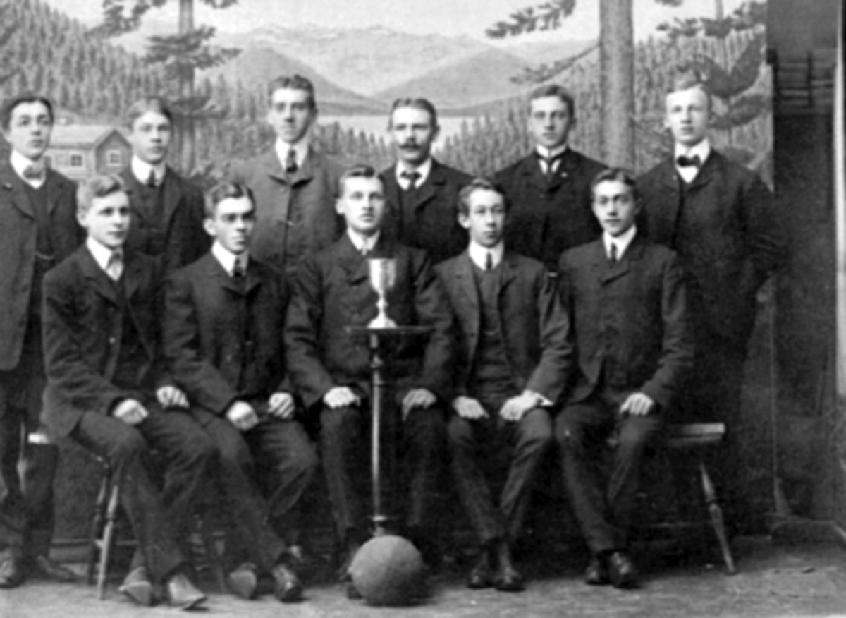 Anno Domkirkeodden, GRUPPE 11 MENN, FOTBALLAG, SPILLERE MED POKAL I STUDIO. H. I. L, HAMAR IDRETTSLAG, FRA VENSTRE: FINN PEDERSEN, RAGNVALD DANIELSEN, SIGURD OLSEN, OLE GUDBRANDSEN, AKSEL HVAL, OSKAR HAGLUND, FORAN FRA VENSTRE: ALF JOHANSEN, JOHS. OLSEN, ASBJØRN RØHNE, BERNHARD HEGSVOLD, SIGURD SVENDSEN