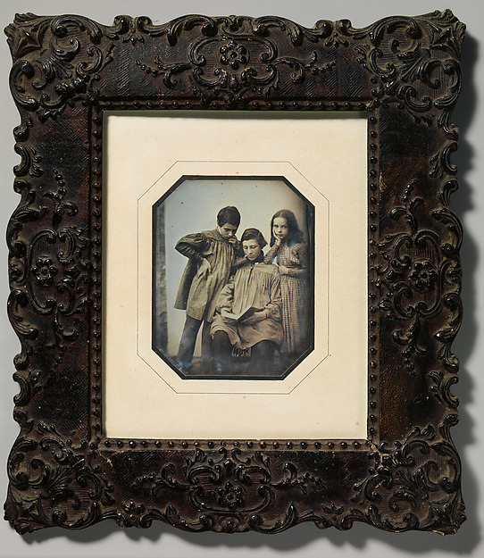 Unknown, [Three Children, One Seated Holding an Open Book, the Other Two Standing, in Front of a Light Background]