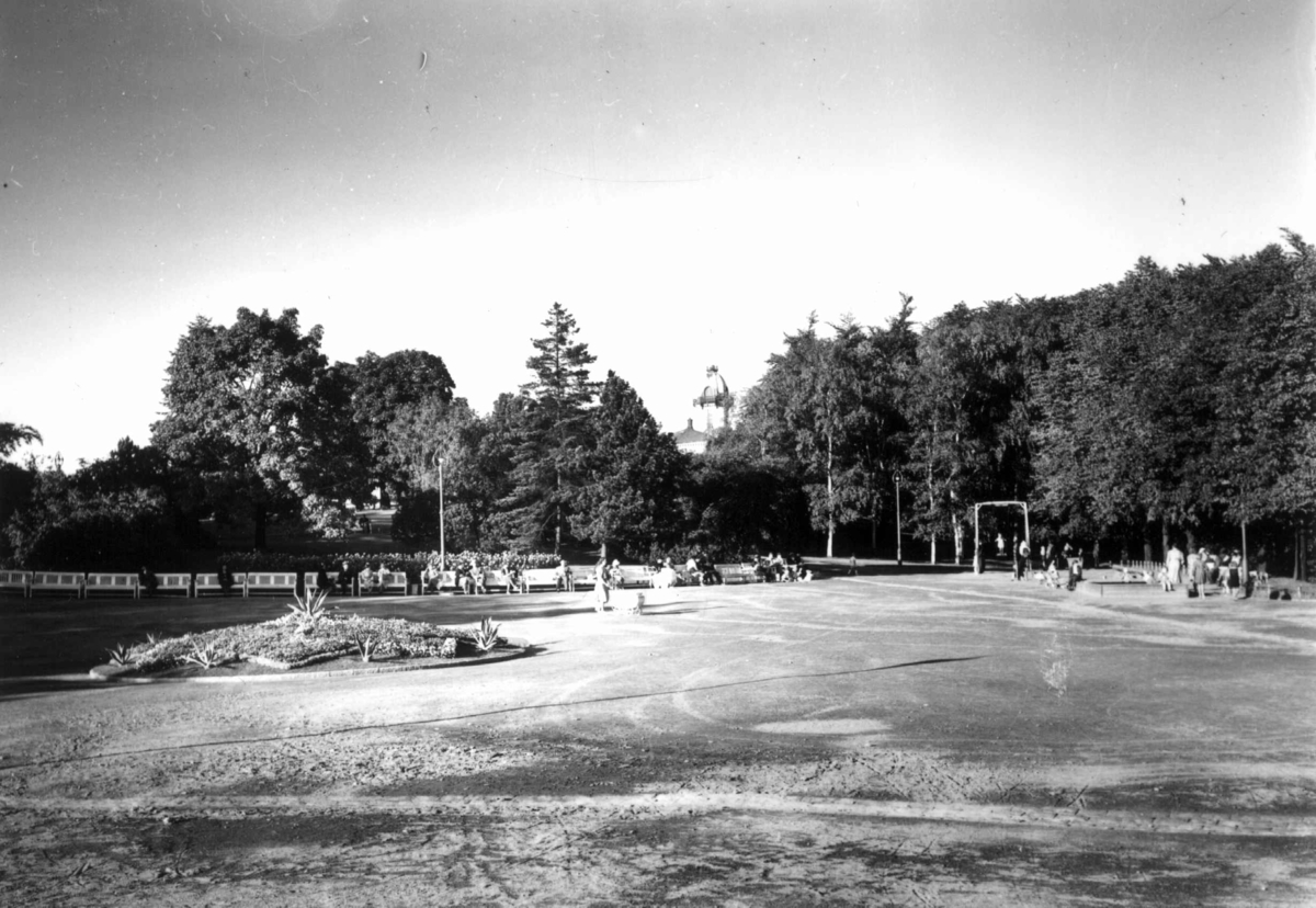 Hermann Christian Neupert, Akershus slott og festning, Oslo 1939. Parken. Voksne er tilskuere til barns lek.