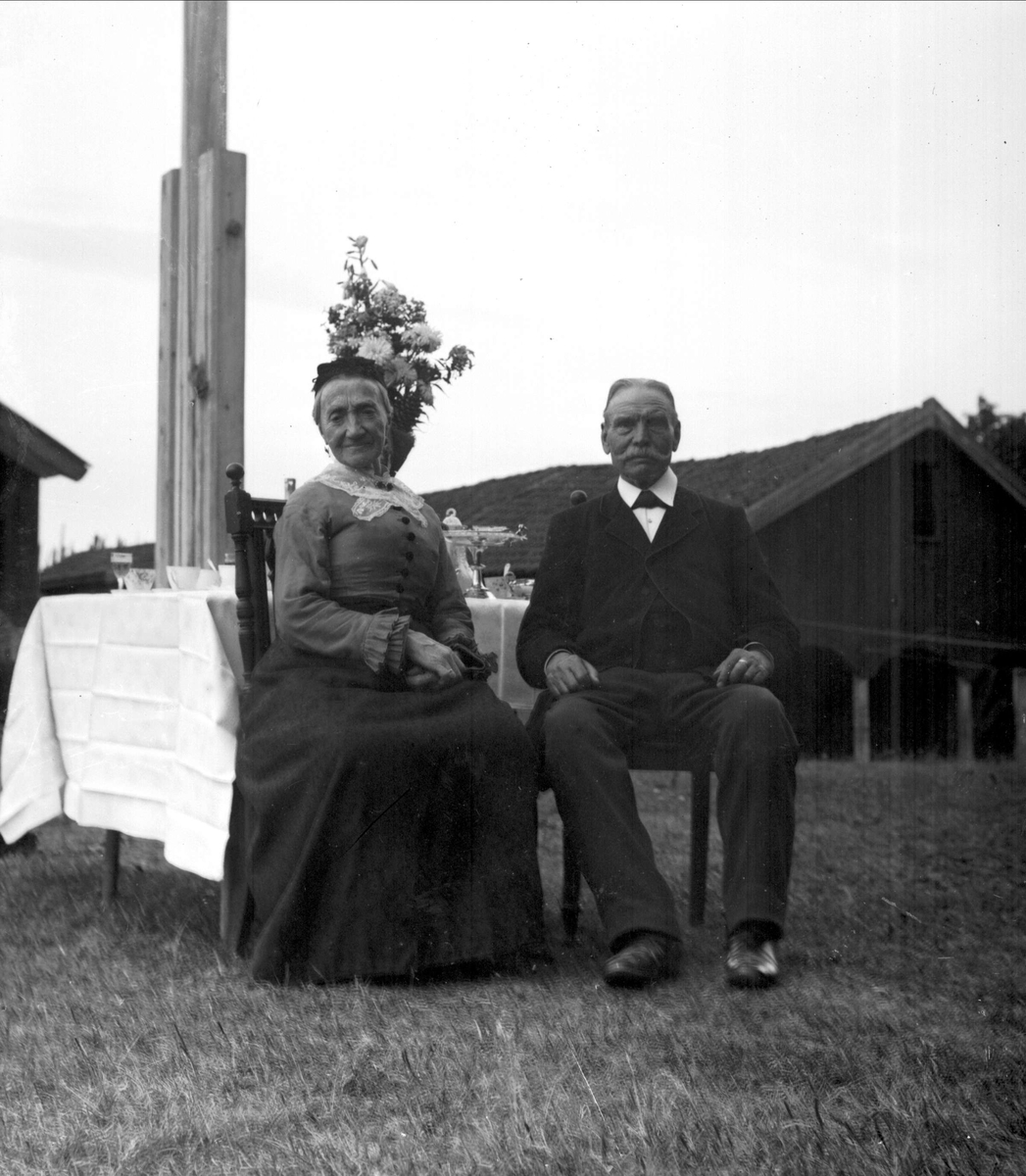 Gustav Borgen, Gruppeportrett, mann og kvinne ved bord i hagen. Vinhandler Larsen sted på Bygdøy.
