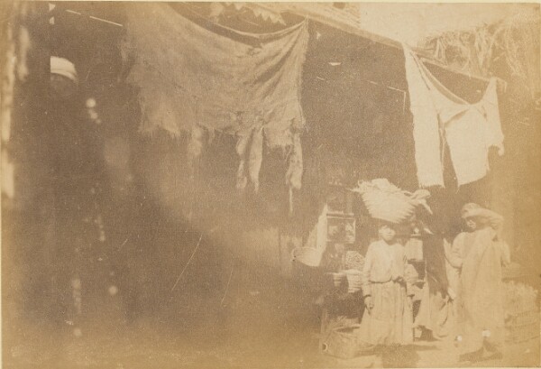 Unknown, [Figures in front of booth]