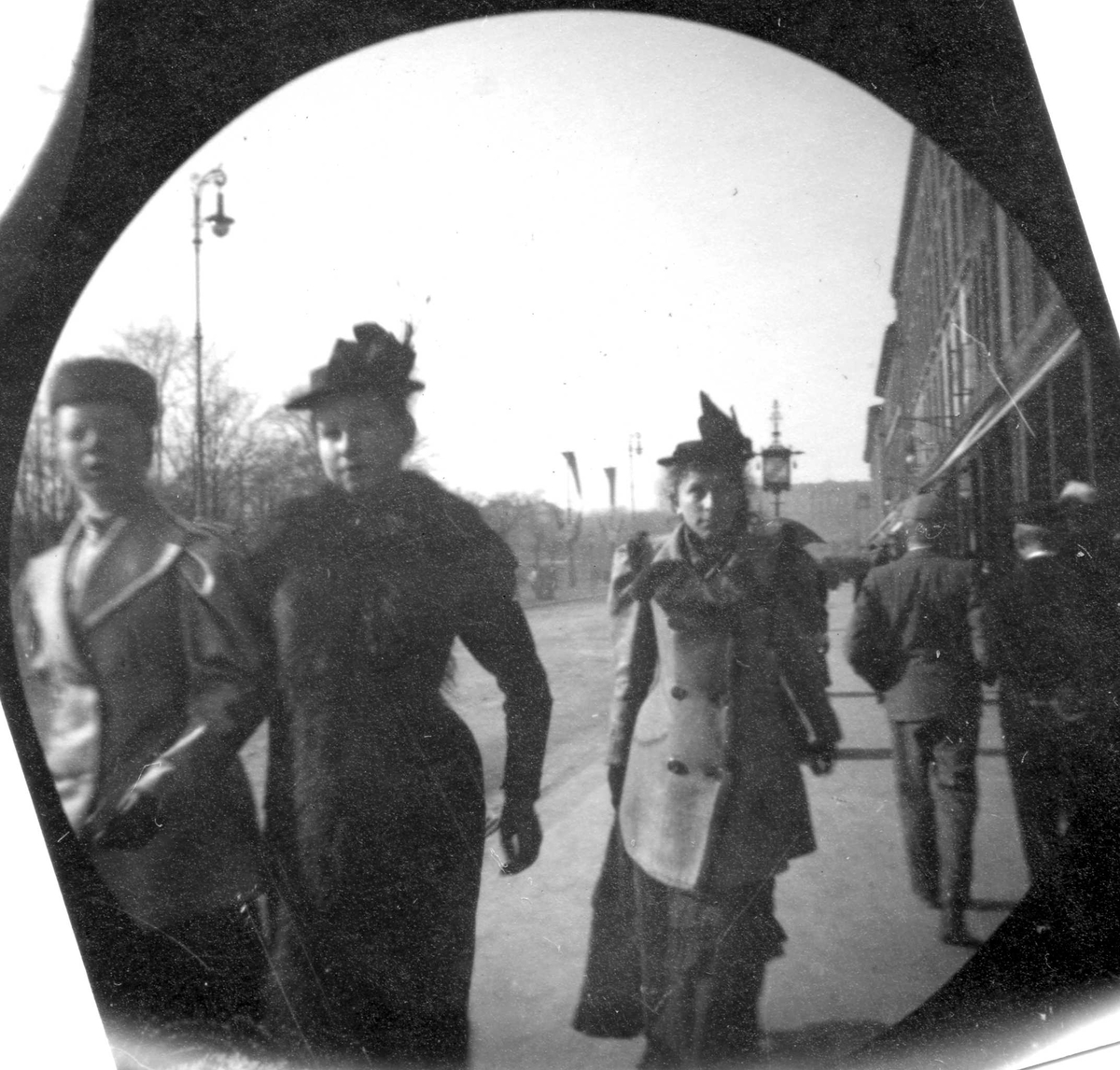 Fredrik Carl Mülertz Størmer, Tre kvinner spaserer på fortau langs Karl Johan, Oslo. To menn går i andre retningen. Bygårder.