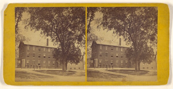 Unknown, [View of a large building with men standing outside, possibly a college dormitory]