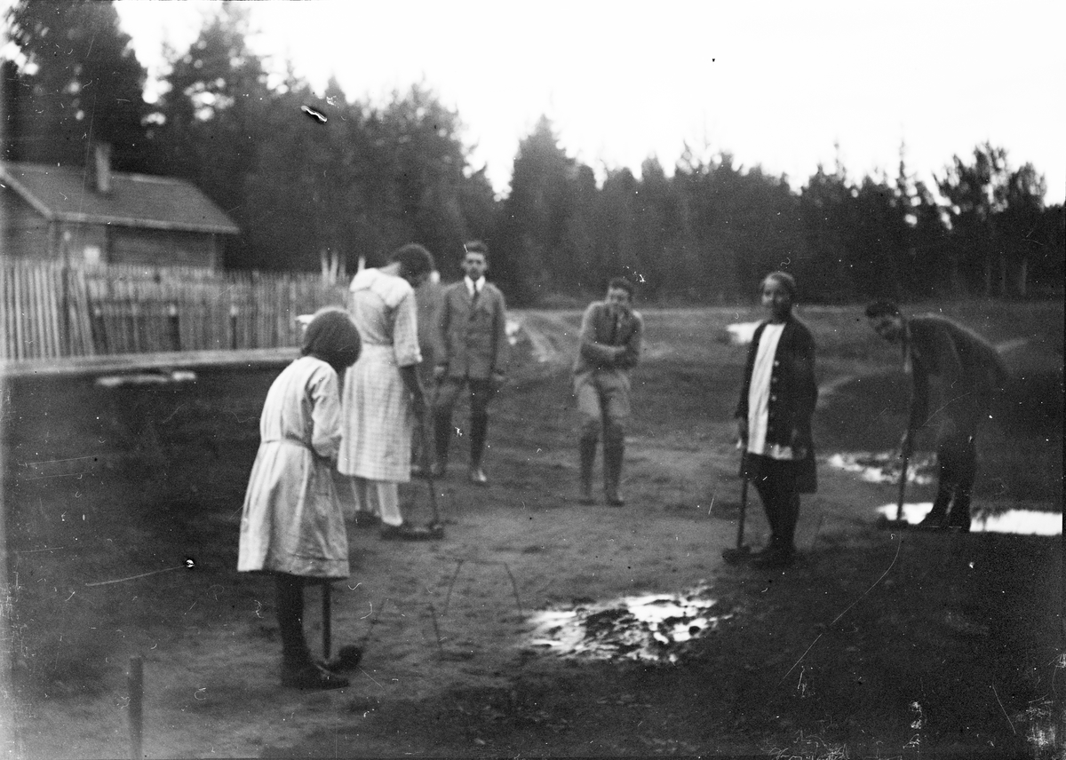Okänd,, Flickor och pojkar spelar krocket ute på gården, sannolikt i Sverige