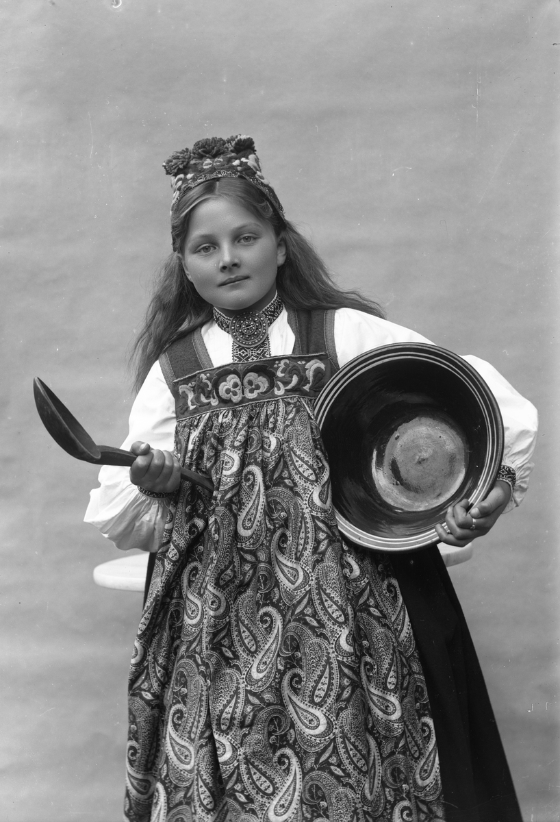Solveig Lund, Studioportrett av kvinne i drakt og skaut, som holder et fat og en sleiv. Bakgrunnen er nøytral.