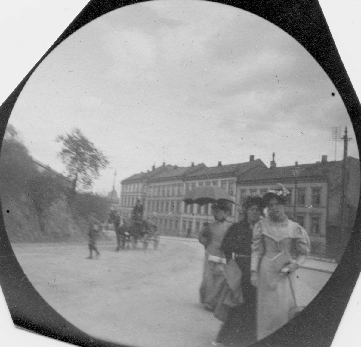 Fredrik Carl Mülertz Størmer, Tre kvinner spaserer i bygate, Oslo. Hestekjøretøy i gata og bygårder i bakgrunnen.