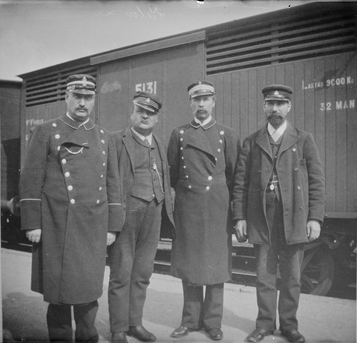 Henri Osti's Fotografiateliér, Grupporträtt - från vänster konduktör, lokförare, överkonduktör och stationskarl på Uppsala centralstation, Uppsala 1890-tal