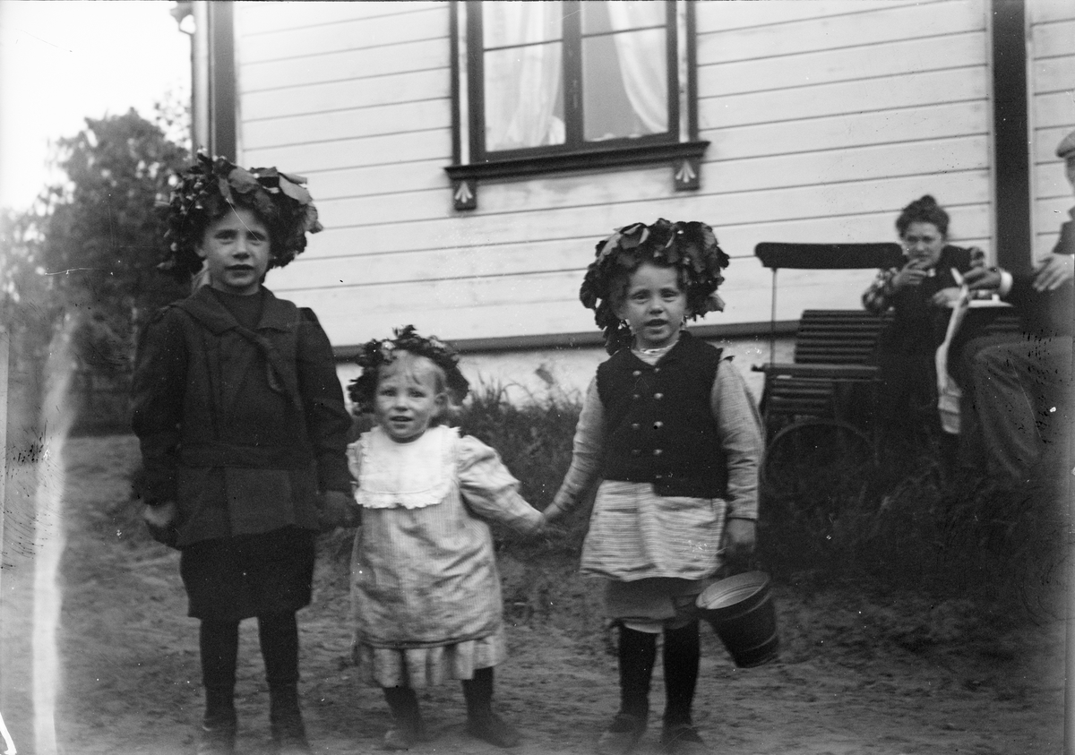 Okänd,, Sannolikt midsommarfirande i Sverige. Roland, Alf och Ingemar Liljefors står framför bostadshus med krans på huvuden. I bakgrunden Christiane Liljefors, sannolikt Sverige