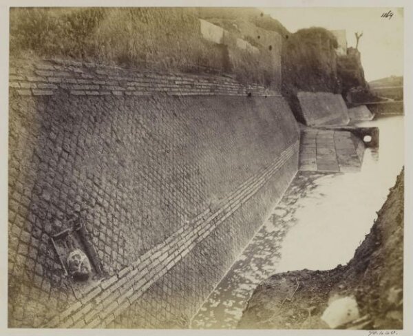 Parker, John Henry, Excavations, 1869 - The Marmorata, or wharf for landing marble, &c., under the Emporium, with an Amphora carved in the wall to indicate the place for landing wine or oil, with Opus Reticulatum of the first century.