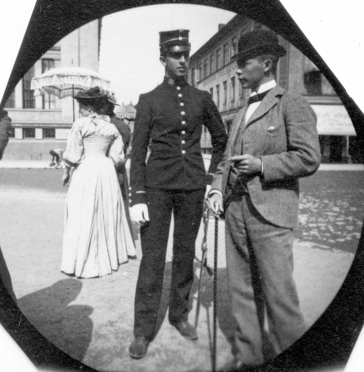 Fredrik Carl Mülertz Størmer, Hermann Reimers i uniform og Aage Halvorsen står på gatehjørne på Karl Johans gate, Oslo, ved Universitetet. De er studenter fra 1892.