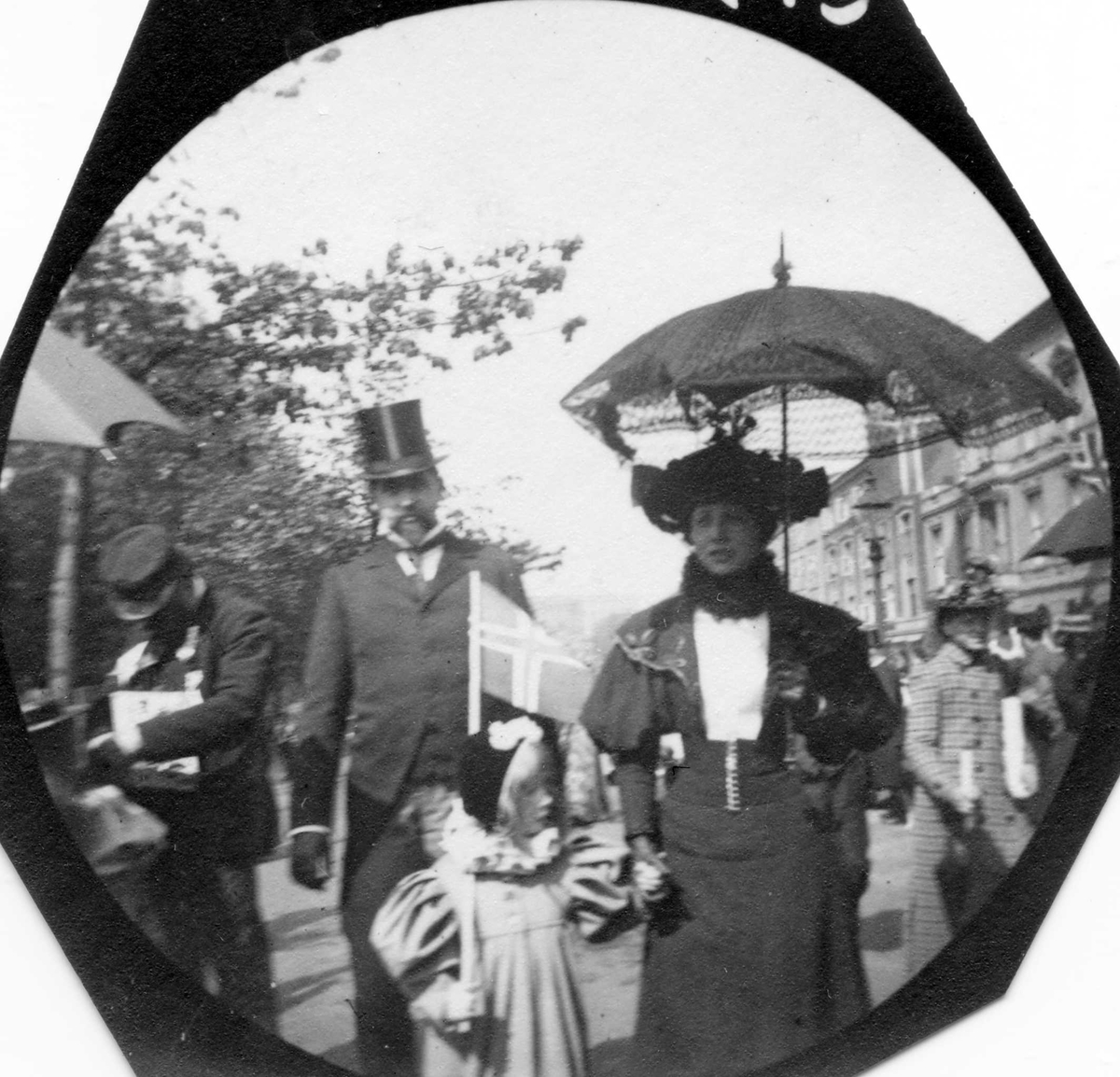 Fredrik Carl Mülertz Størmer, Skuespiller Ludvig Bergh, hans kone Milly (tidligere Thaulow) og datter på Karl Johans gate i Oslo 17. mai, med norsk flagg, antakelig.Fotografert etter 1906.