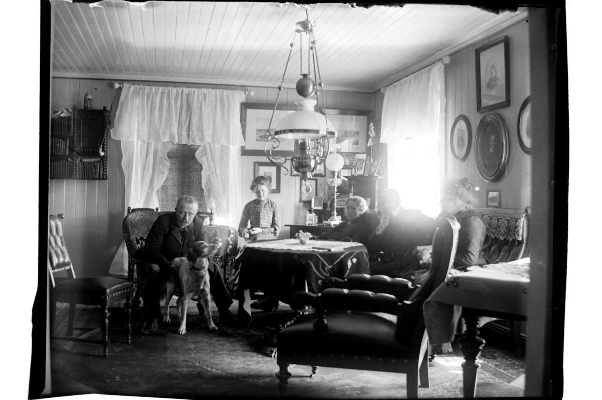 Rolf Sr. Sundt, Halfdan Sundt med hund, ukjent kvinne og hustru Rebekka Sundt rundt et bord i stue, antagelig i hans hjem på Gol.