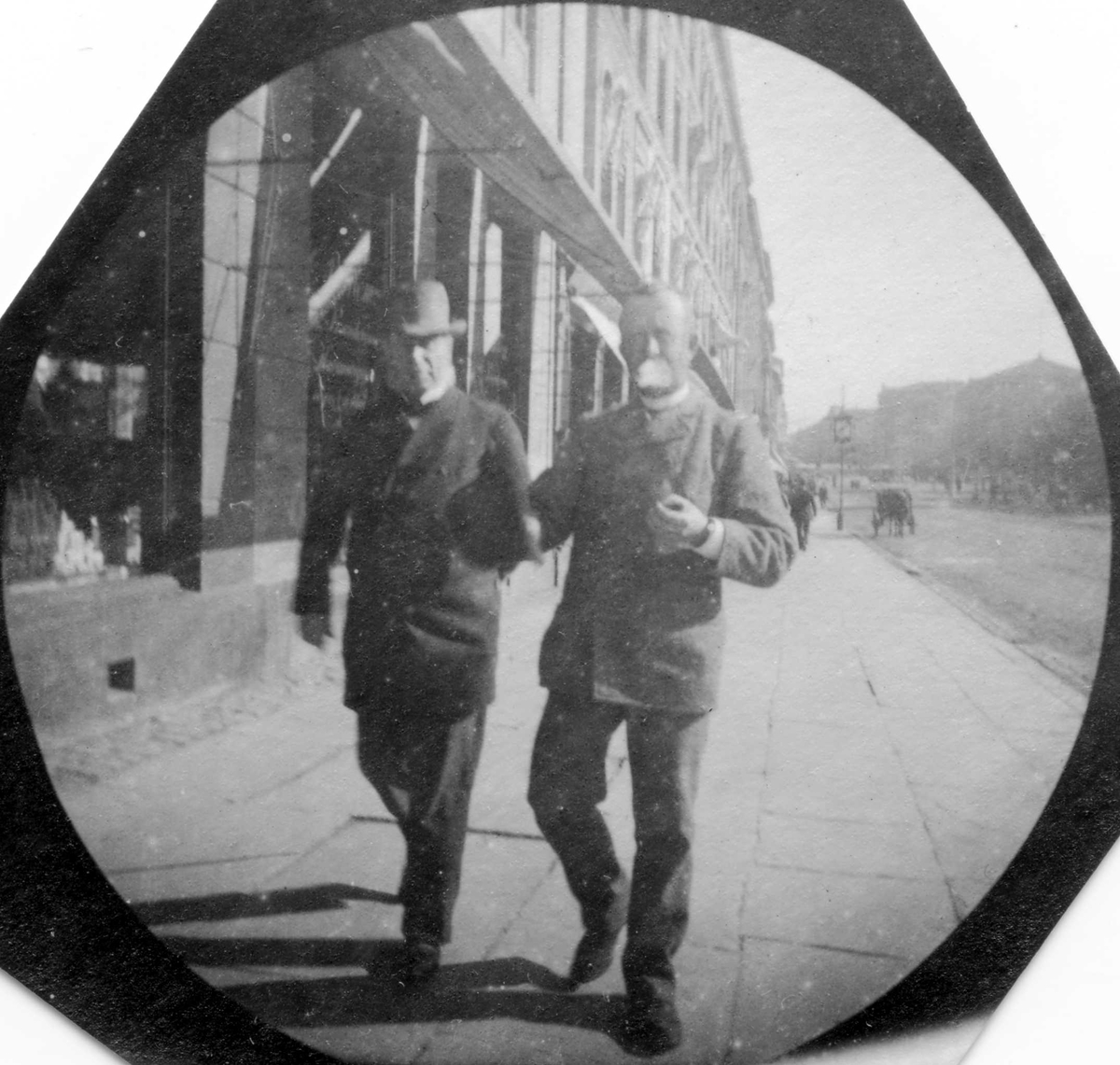 Fredrik Carl Mülertz Størmer, To menn spaserer langs Karl Johans gate, Oslo. Butikker, hestekjøretøy og Stortinget i bakgrunnen. Professor A. Blytt til høyre, røkende.
