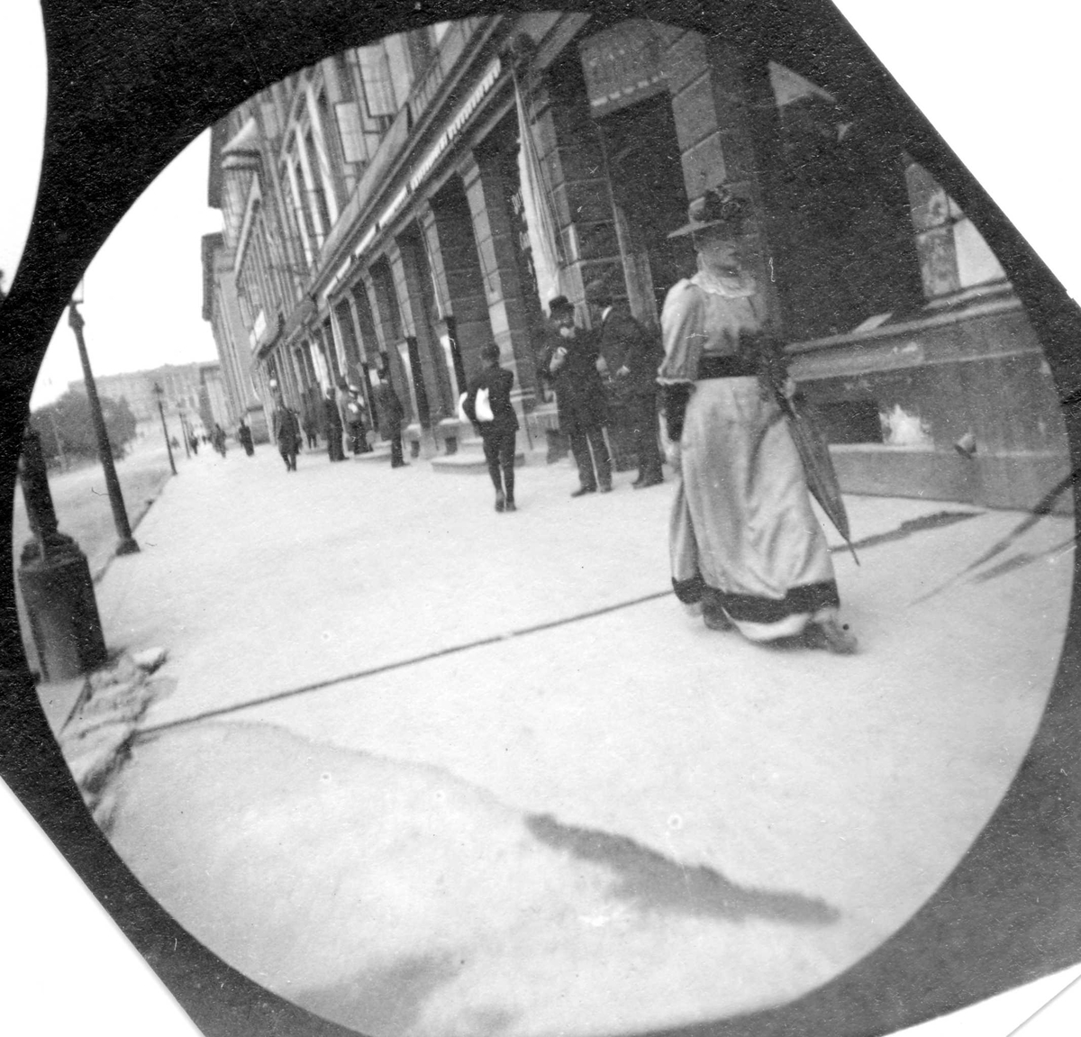 Fredrik Carl Mülertz Størmer, Frk. Sommerfelt spaserer på fortau langs Karl Johan, Oslo. Slottet skimtes.