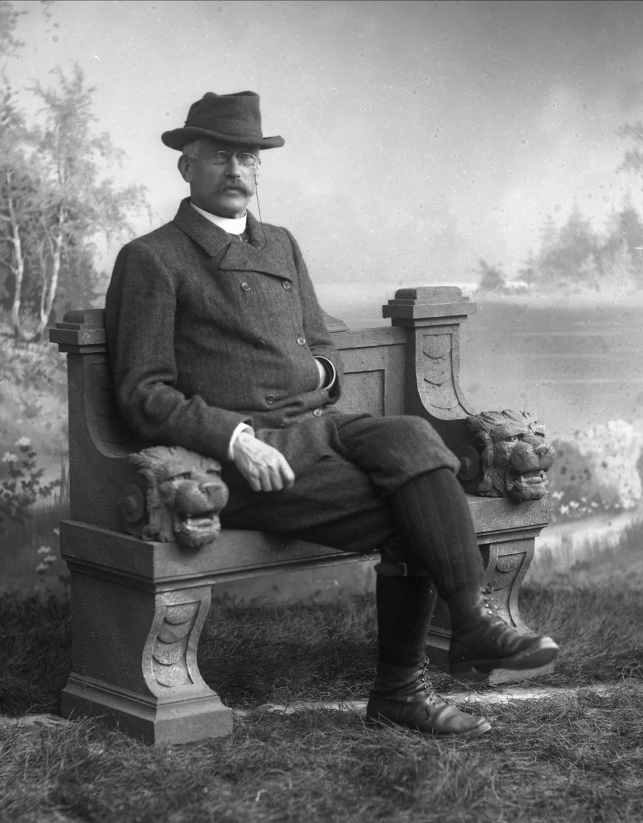 Gustav Borgen, Portrett, mann i ytterklær på benk. Strømper og nikkers.