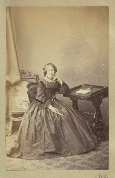 Unknown, [Portrait of woman sitting next to writing desk]