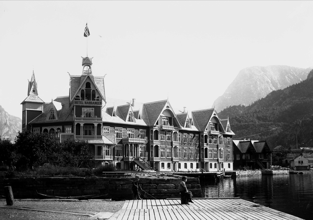 Solveig Lund, Odda i Hardanger.Hardanger Hotell. Fjellandskap i bakgrunnen. Foran på brygga ut mot Sørfjorden står to unggutter.