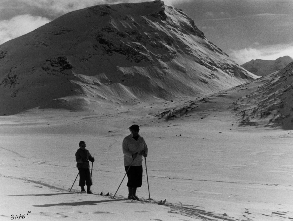 Anders Beer Wilse, Skiløpere ved Styggehø i Jotunheimen med snødekte fjell og sol.