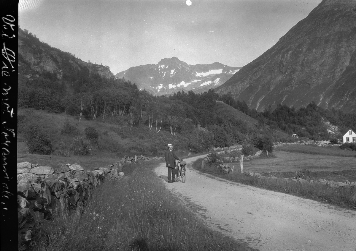 Kristian Heramb, Øye i Norangdal, Ørsta. En mann med sykkel på en vei. Landskap.