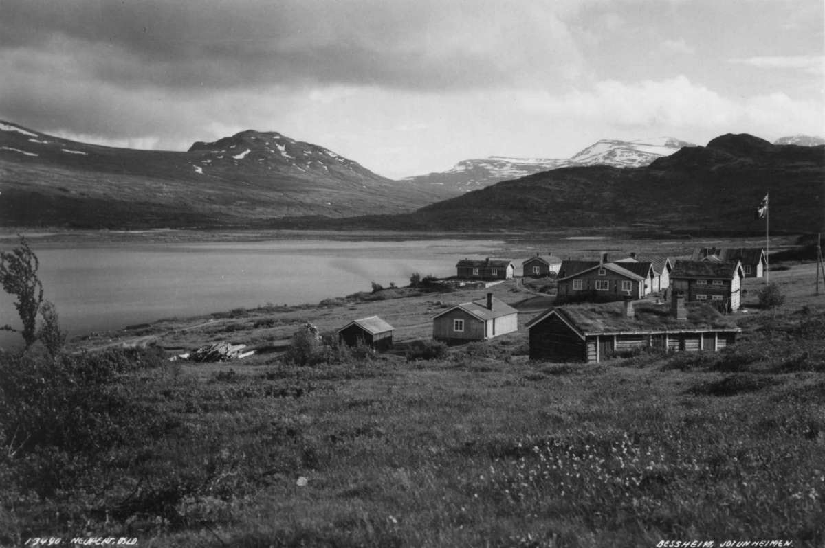 Hermann Christian Neupert, Bessheim, Vågå 1935. Oversiktsbilde. Turisthytte i Jotunheimen. Omgitt av landskap med vann og f ell. Snø på toppene.