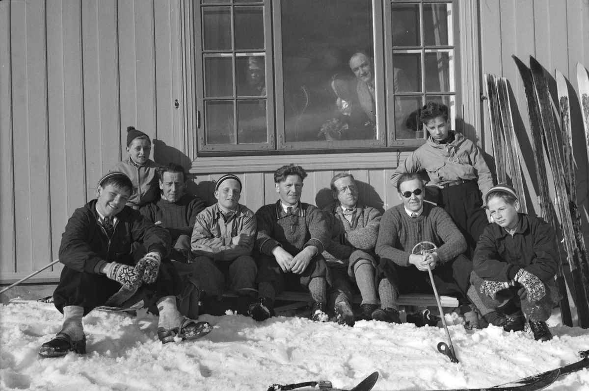 Håkon Prestkværn, Ukjent gruppe mennesker soler seg i husveggen på skitur. Ski.
