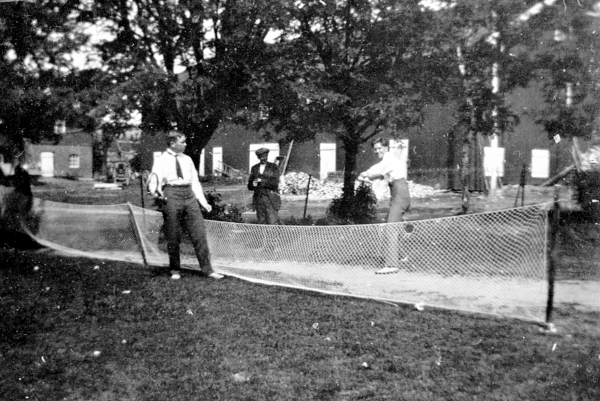Anno Domkirkeodden, To menn spiller tennis på tunet på Granerud gård, Brumunddal.