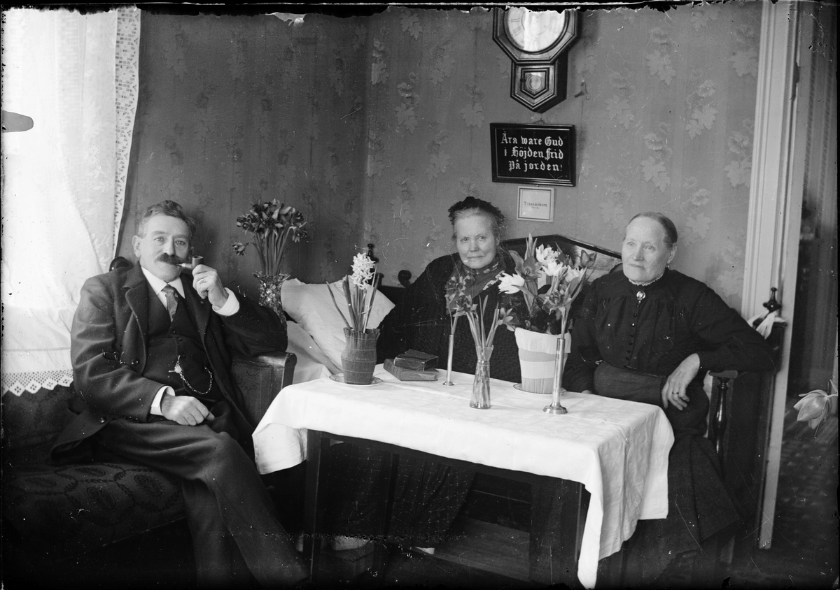 Skötsner-Edhlund, J H Hermansson och två kvinnor vid bord med blommor, Östhammar, Uppland
