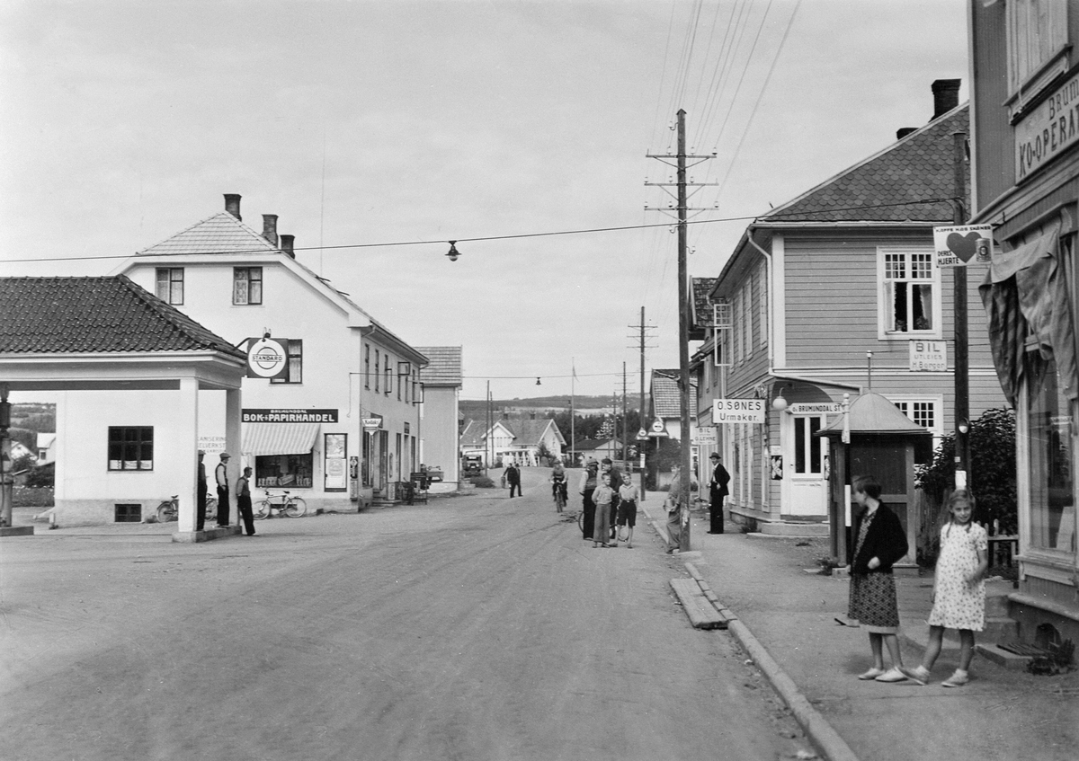 Anno Domkirkeodden, Brumunddal med riksveg 50 gjennom sentrum. Standard bensin, Sandbakken bensinstasjon, O. Sønes, Brumunddal Bok & Papirhandel.