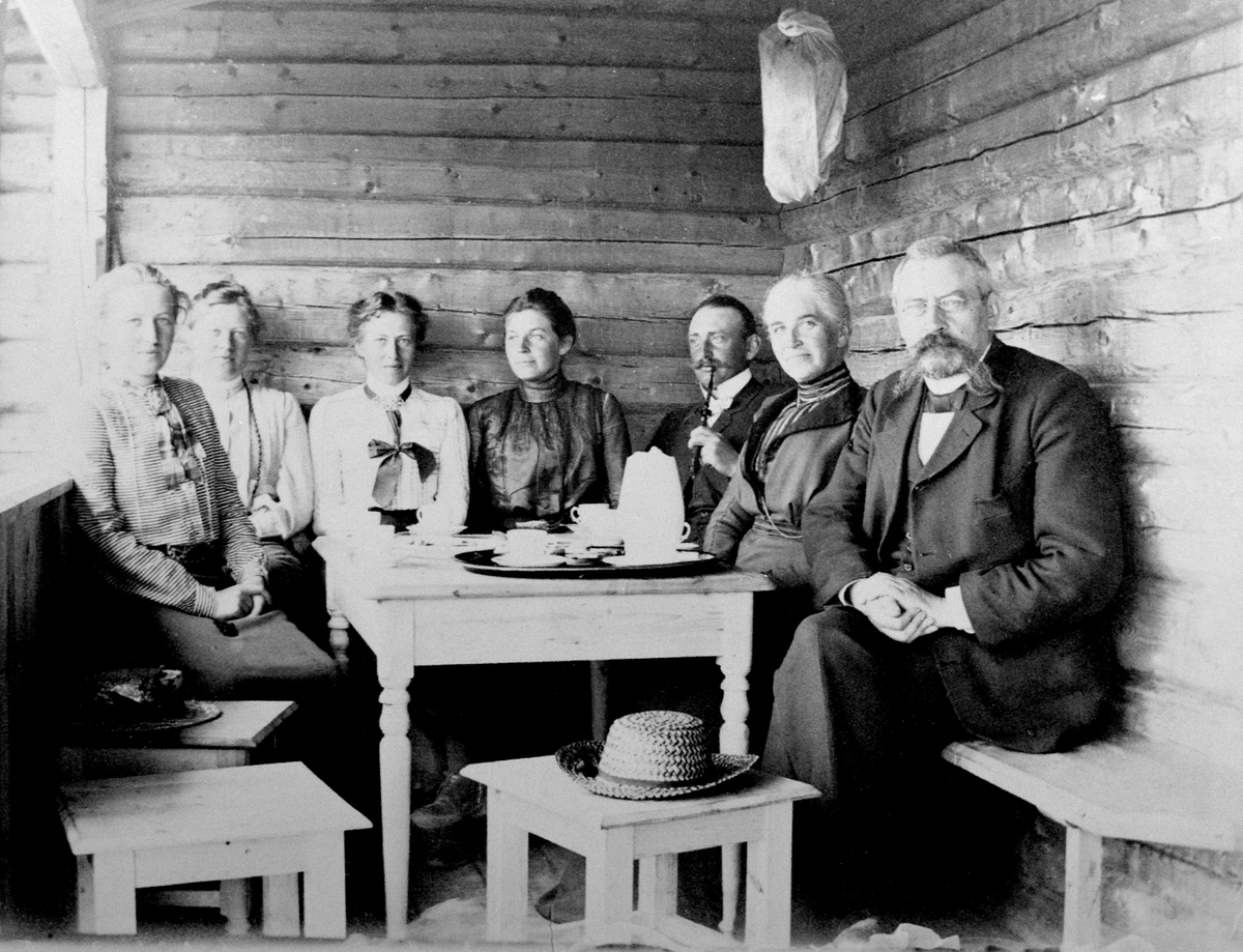 Anno Domkirkeodden, Kaffekos på veranda i Skriverstuen, Bredalhytta. Første hytte i Philske sameie, Gammelskolla, Ringsakerfjellet. Fra venstre er Tulla Hersaug, Mimi Løken, Lally Skappel, Helga Bredal 1877 født Bugge, Peter Bredal 1872, Marie Bredal 1840 født Ravn, sorenskriver P.E. Bredal f.1828.