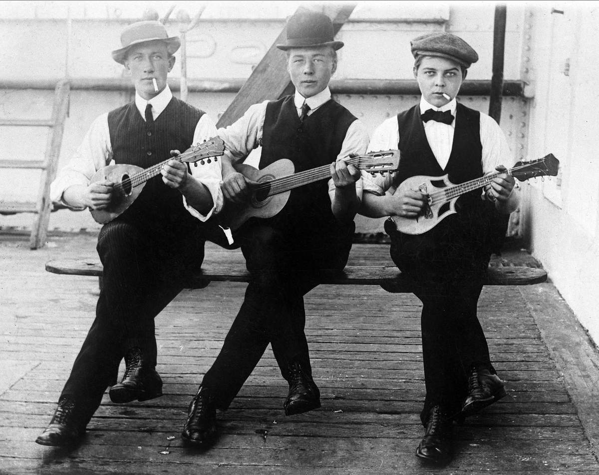 Gustav Borgen, Gruppeportrett, tre musikere, et band ombord på en båt. Mandoliner og gitar.