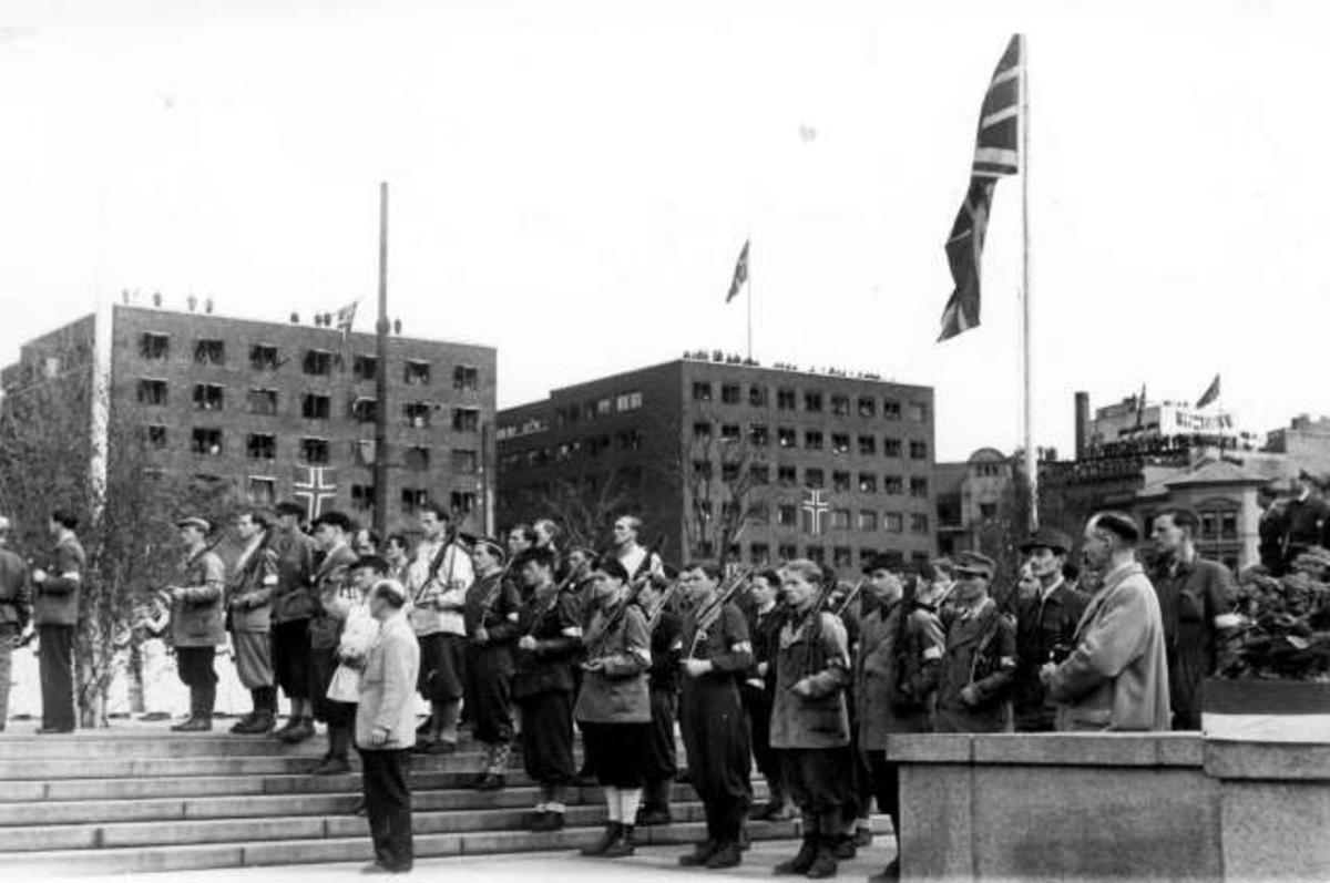 Anders Beer Wilse, Fra Oslo under fredsdagene i 1945. Fra Honnørbrygga, der flaggene vaier og menn med gevær,antagelig fra hjemmefronten, står oppstilt. Antagelig fra 13.mai ved Kronprins Olavs ankomst.