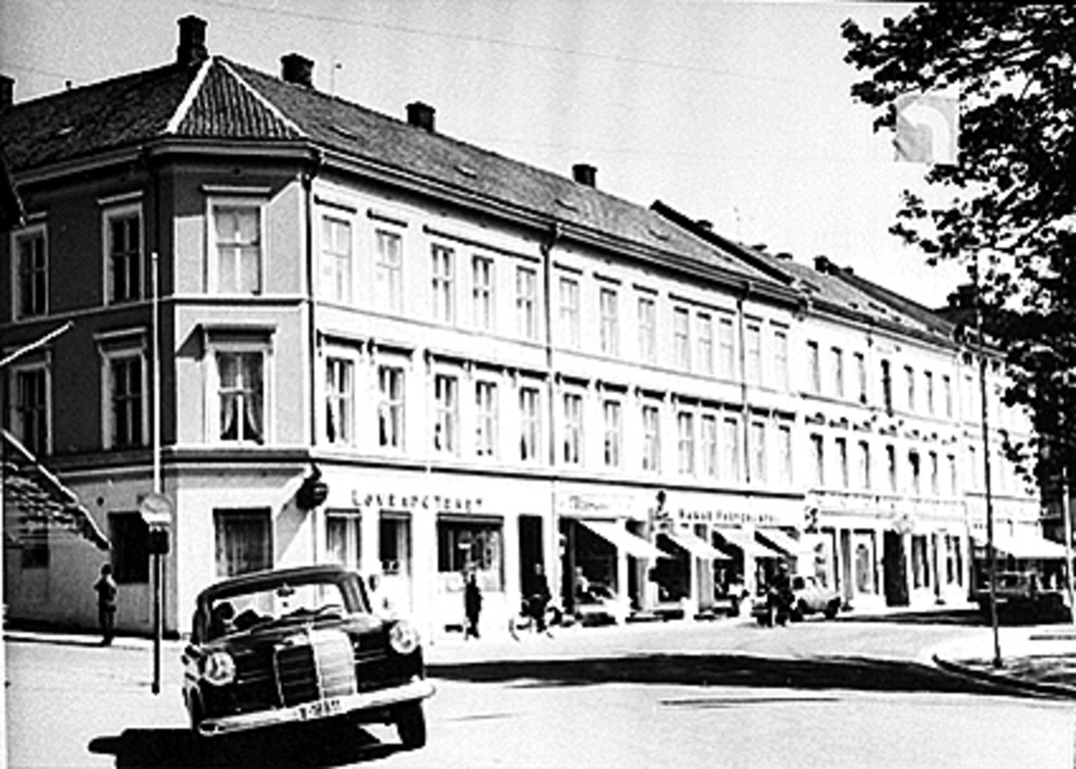 Anno Domkirkeodden, EKSTERIØR STRANDGATA 55, LØVEAPOTEKET, PARKERT BIL Y-18911, Løveapoteket var Hamars andre apotek, og åpnet sine døre 31. oktober 1891 i Strandgata 55. Her ble apoteket værende fram til det flyttet til Torggata 72 i 1975. Fra før av fantes Hamar Apothek som startet sin virksomhet i 1852. Senere skul…