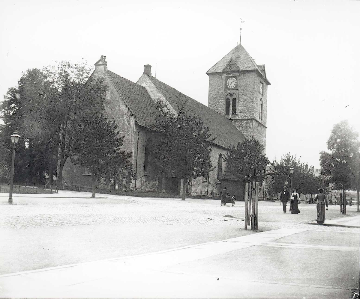 Tom Kent, Kirke i Trondheim ved gate med allé. Mann med håndkjerre. (Vår Frue kirke (Mariakirken) )