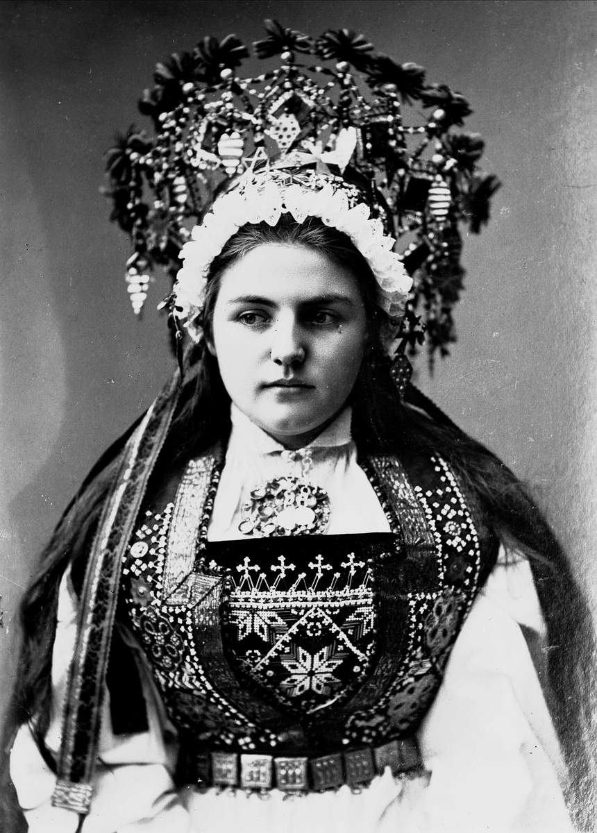 Solveig Lund, Studiofotografi av kvinne kledd i brudedrakt og brudekrone fra Hardanger i Hordaland. Brystutsnitt.Frontal vendt. Ser ut mot høyre.