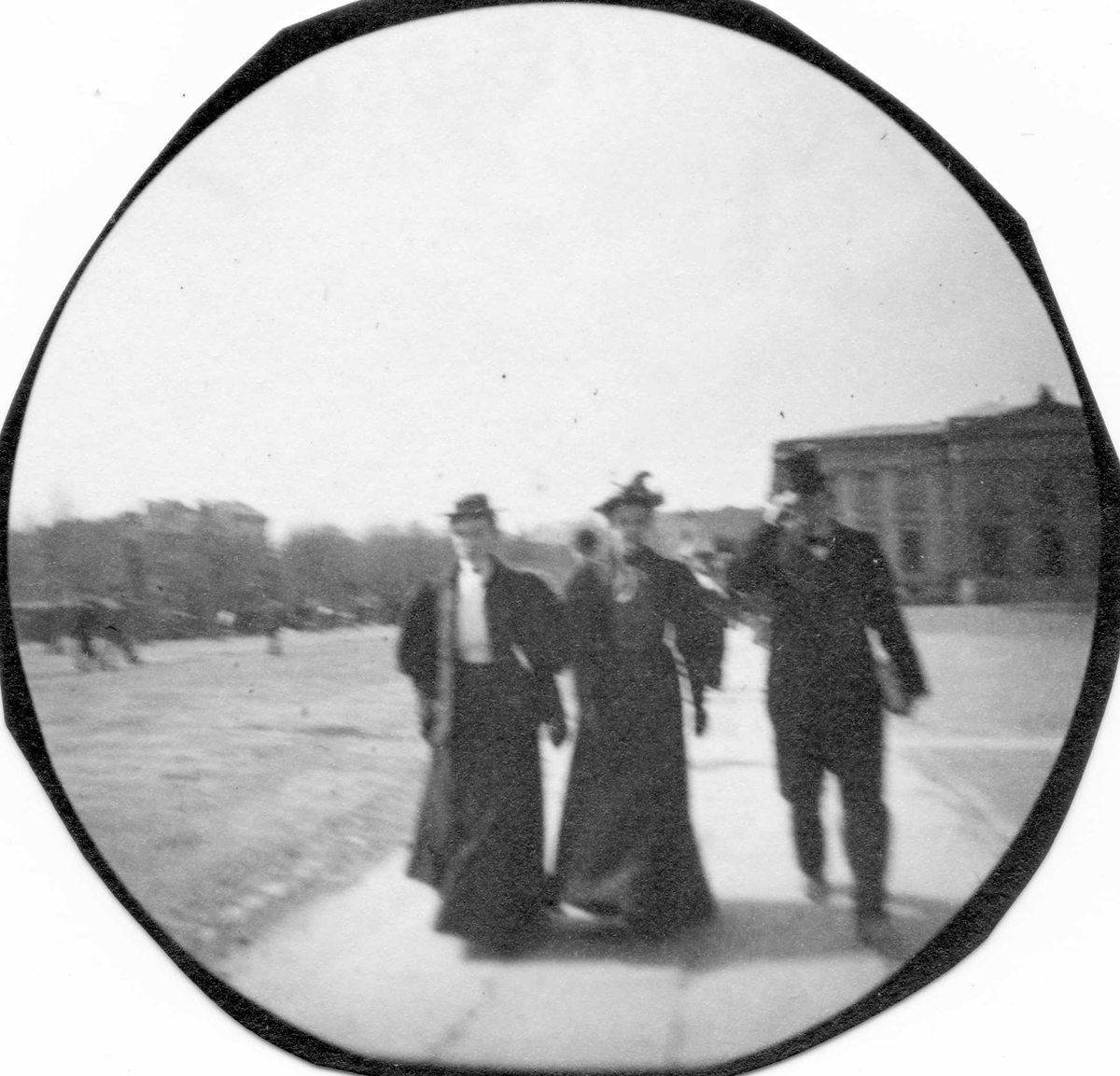 Fredrik Carl Mülertz Størmer, Gruppe spaserer langs Karl Johans gate, Oslo, med Universitetet, Slottet og Nasjonalteateret i bakgrunnen. Fra venstre: Lol Melbye, gift Rohde, Lil Melby, gift Nissen, Hartvig Nissen.