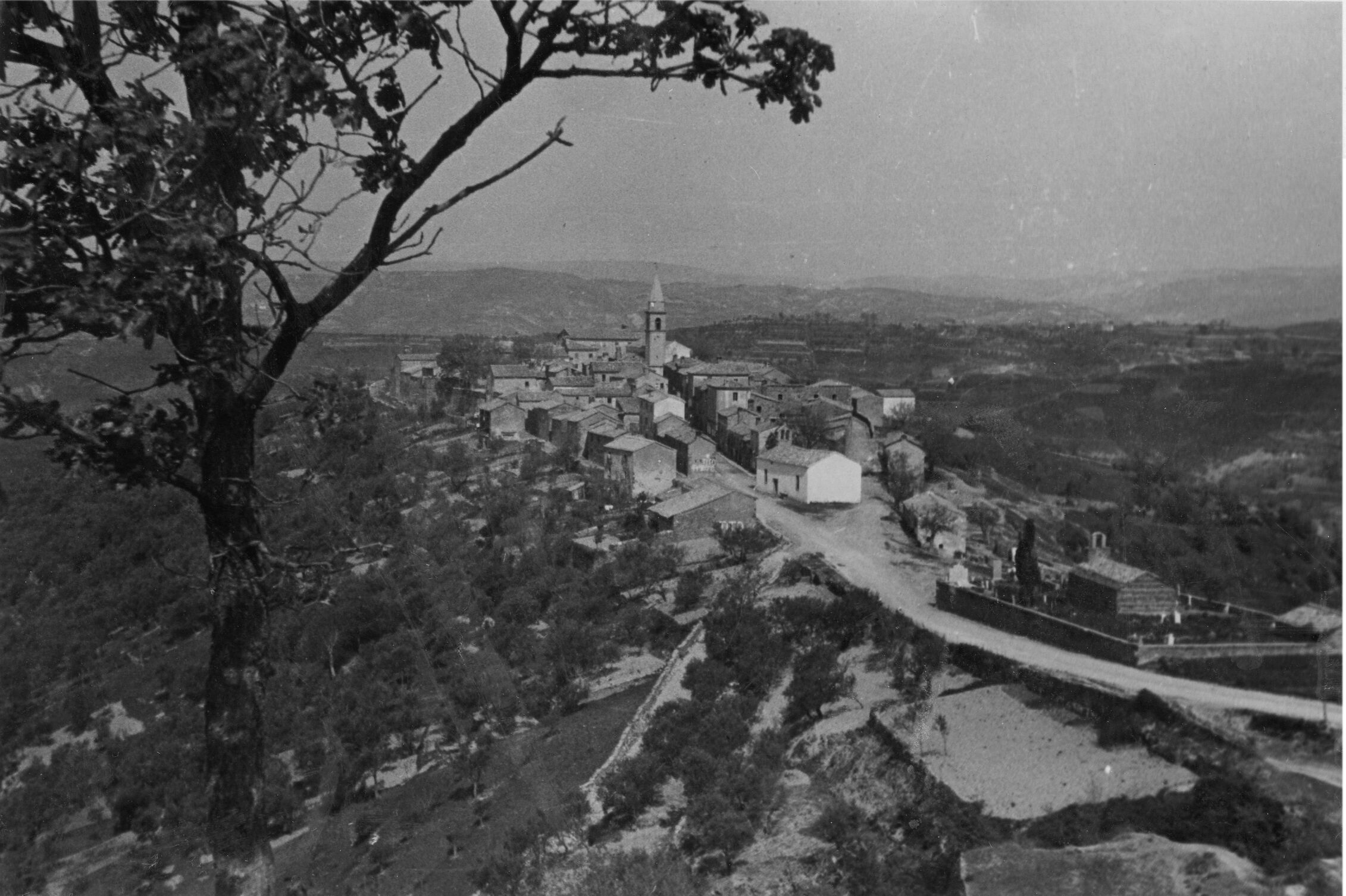 Branko Fučić, Draguć (Cerovlje), panorama s jugoistoka: desno grobljanska kapela sv. Elizeja, romanička; vidi se krov s kombiniranim krovnim pokrovom iz kupe i škrilja (iza popravka)