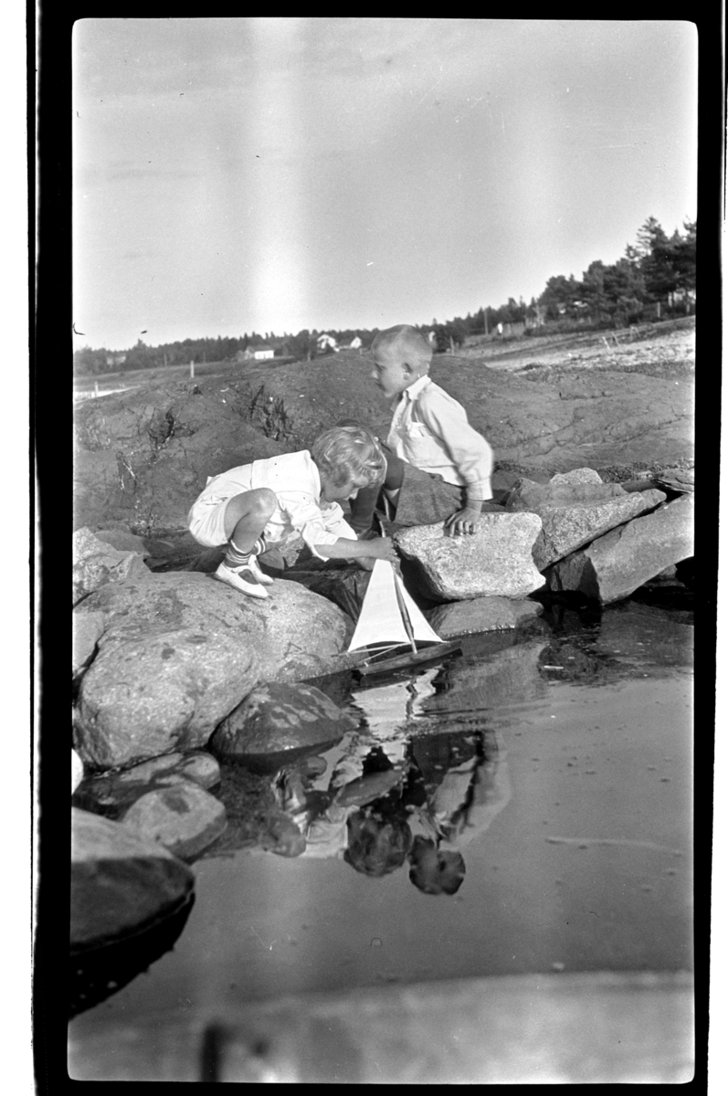 Rolf Sr. Sundt, Brødrene Julius og Rolf jr, Sundt leker med seilbåt i fjæra, Slagen. Fotografert 1925.