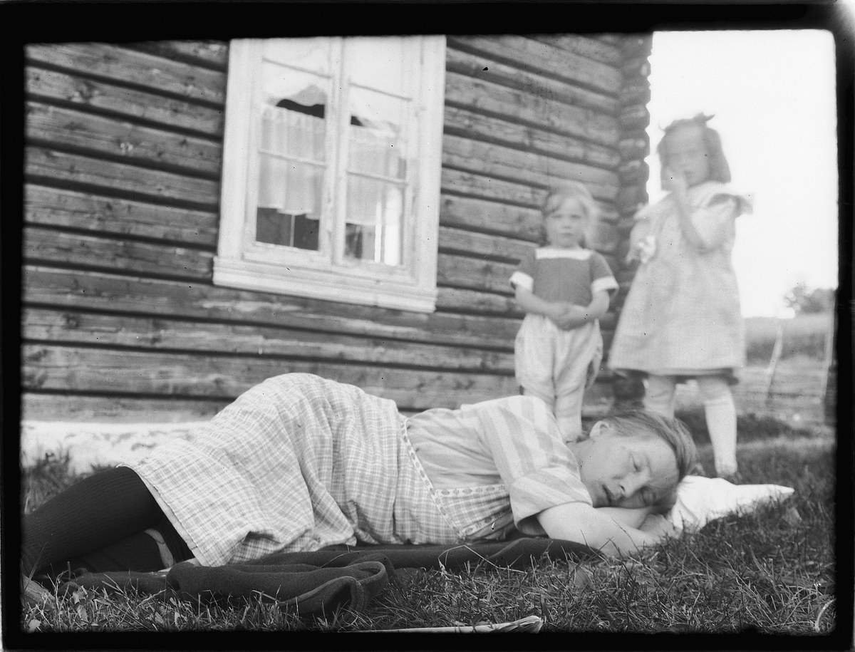 Ragnvald Andersen, Ukjent kvinne sover i gresset, to barn i bakgrunnen.