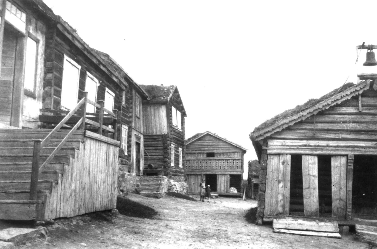 Anna Grostøl, Antagelig Lesja, Oppland 1934. Gårdstun med tømmerhus og stabbur.