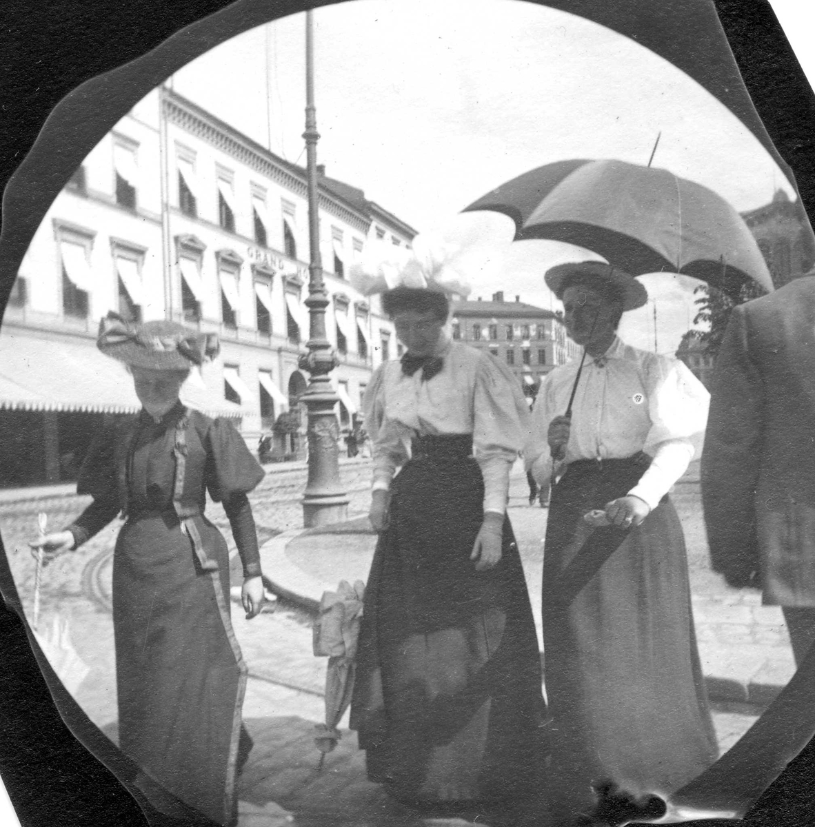 Fredrik Carl Mülertz Størmer, Frk. Dahr, frk. L*Orange og frk. Selma Faye, senere fru Zimmer, spaserer langs Karl Johans gate, Oslo, med Grand Hotel på den andre siden.