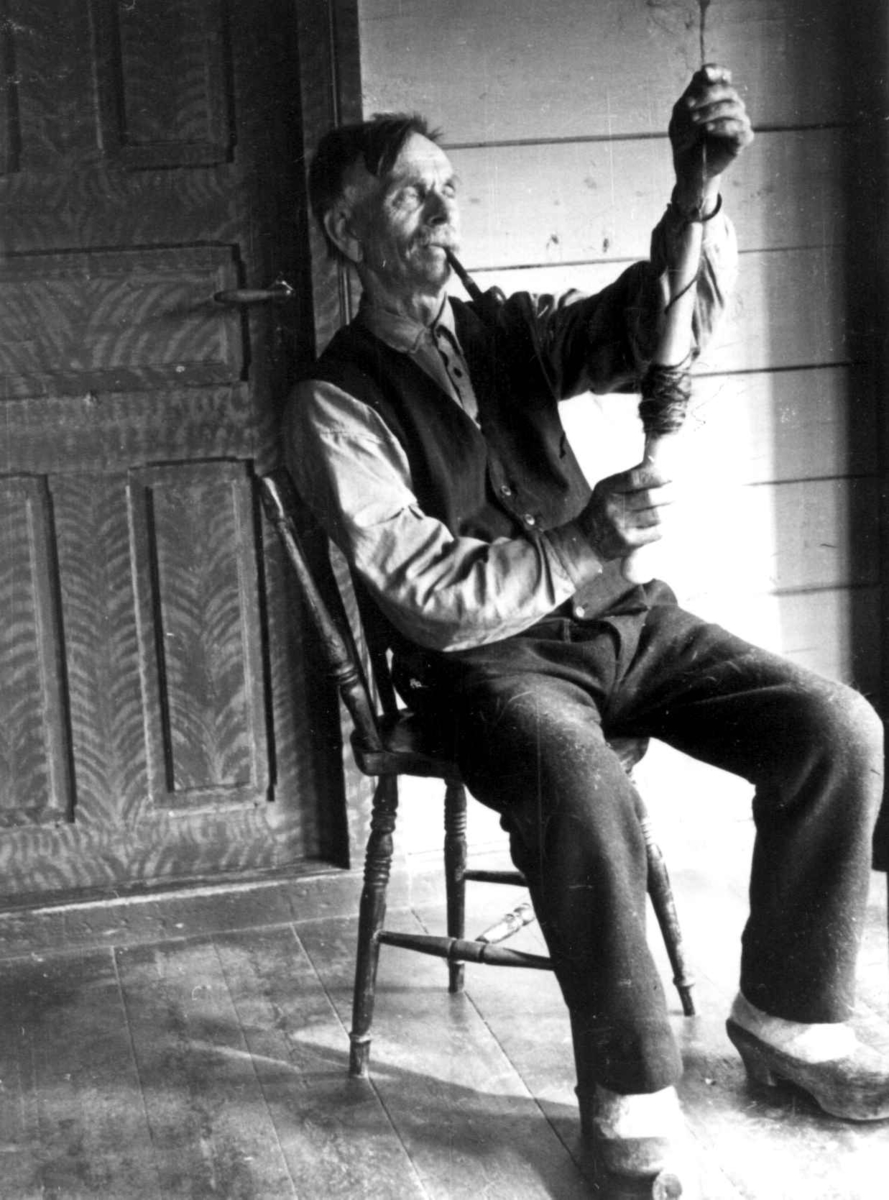 Anna Grostøl, Sigmund Rudlende på Rossevatn spinner på håndrokk. Eiken, Hægebostad, Vest-Agder 1941.