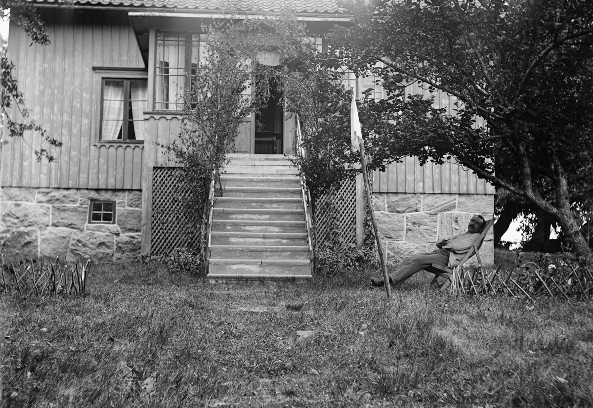 Okänd,, Ruben Liljefors vilar i solstolen ute i trädgård framför bostadshus, sannolikt midsommar i Sverige