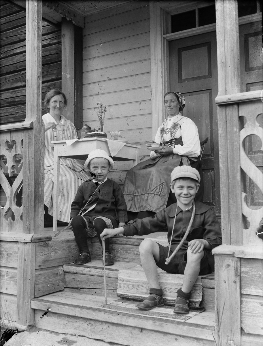 Josef Ärnström, Nora Ärnström och en kvinna klädd i folkdräkt vid kaffebordet. Sannolikt Rolf och Kalle Ärnström på trappen