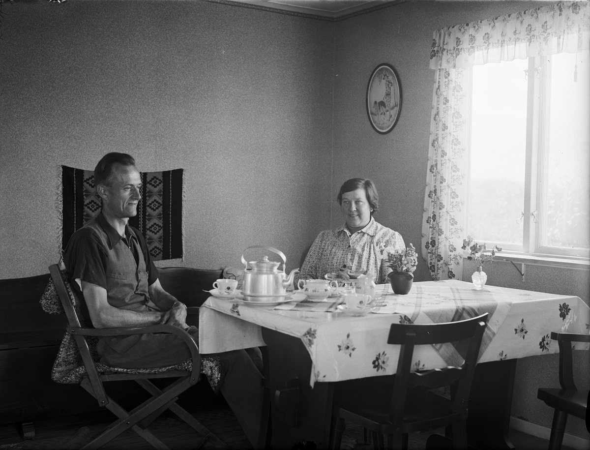Paul Sandberg, "En interiör från stugan nr 133, där hr Severin Jansson och hans maka just njuta av en kaffepaus i trädgårdsarbetet", Tunabergskolonin i Tuna backar