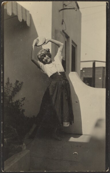 Louis Fleckenstein, [Woman Posing Before House with Tambourine]