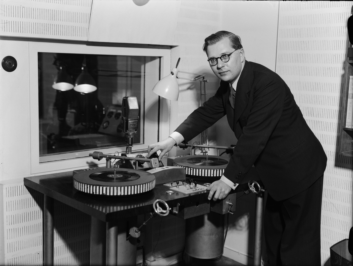 Paul Sandberg, "139 upsalaprogram i radion under 1942" - Gösta Knutsson framför det nya grammofonbordet i Uppsala rundradiostation, Universitetshuset, Uppsala februari 1943