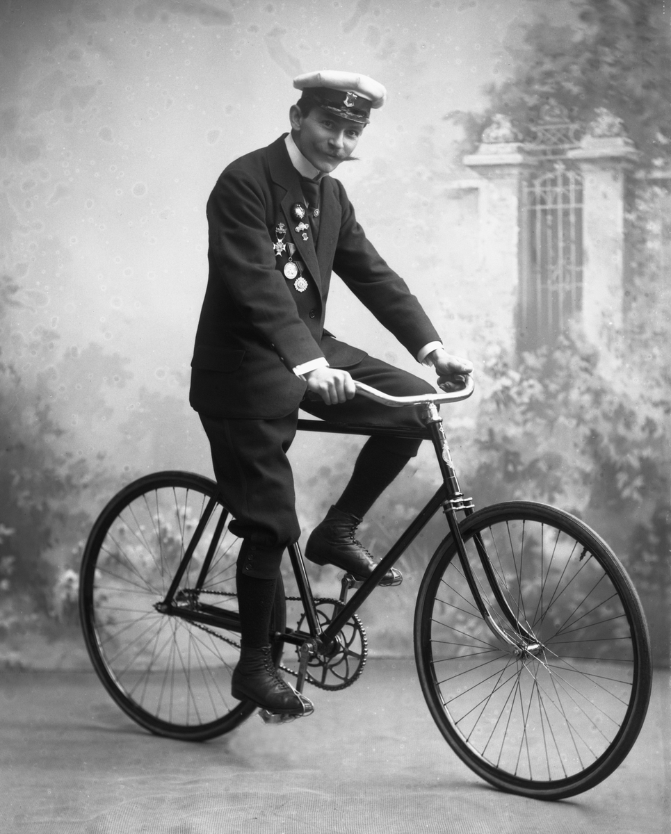 Gustav Borgen, Portrett, mann med uniformslue, medaljer og sykkel.