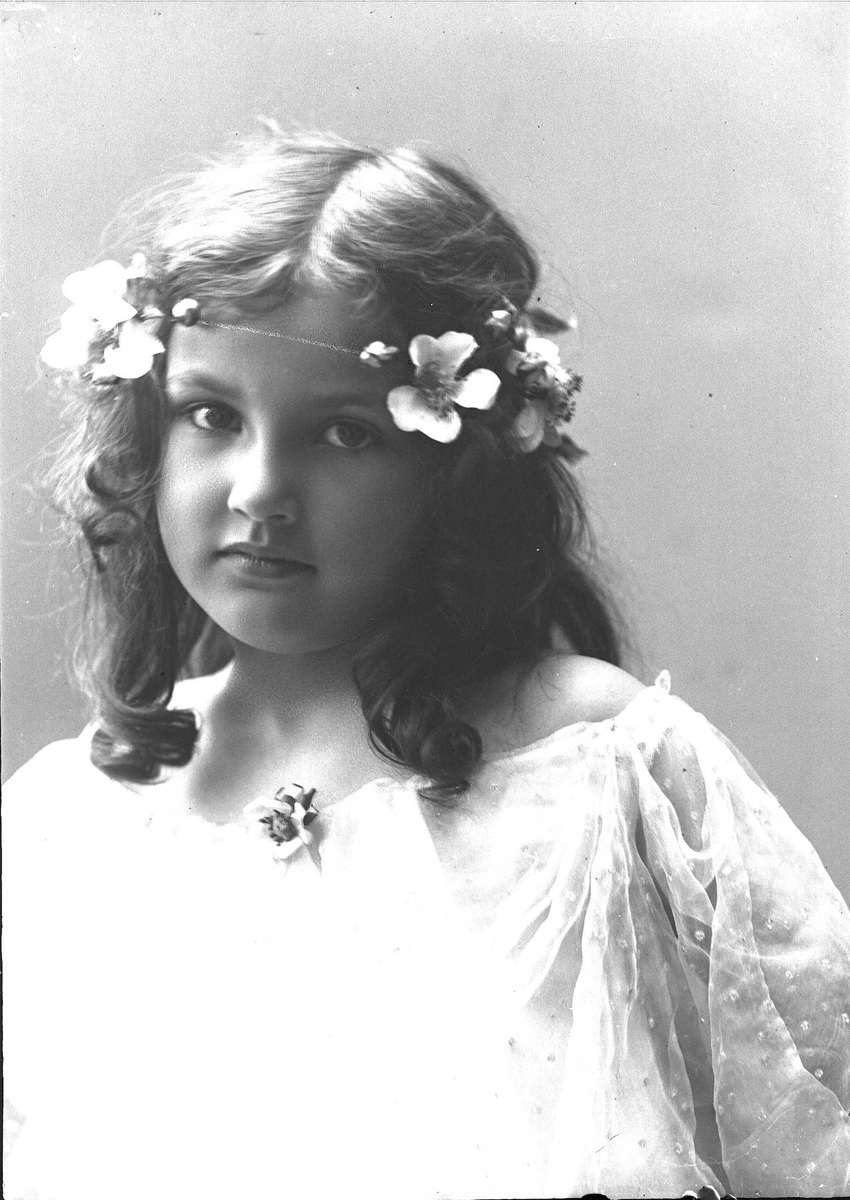 Solveig Lund, Brystportrett av jente med kjole og blomster i håret - ser på betrakteren.