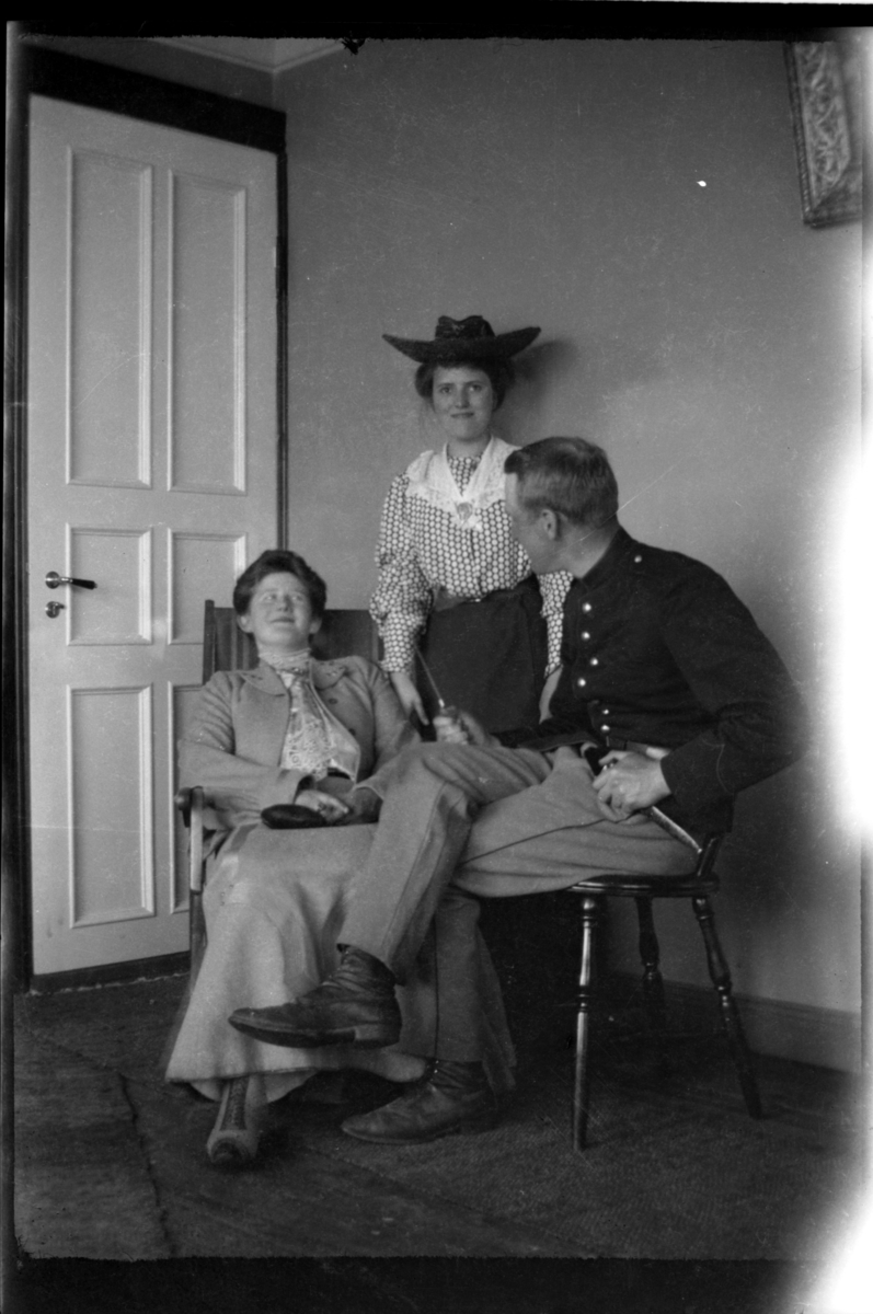 Rolf Sr. Sundt, To kvinner og en mann, alle ukjente, fotografert innendørs.